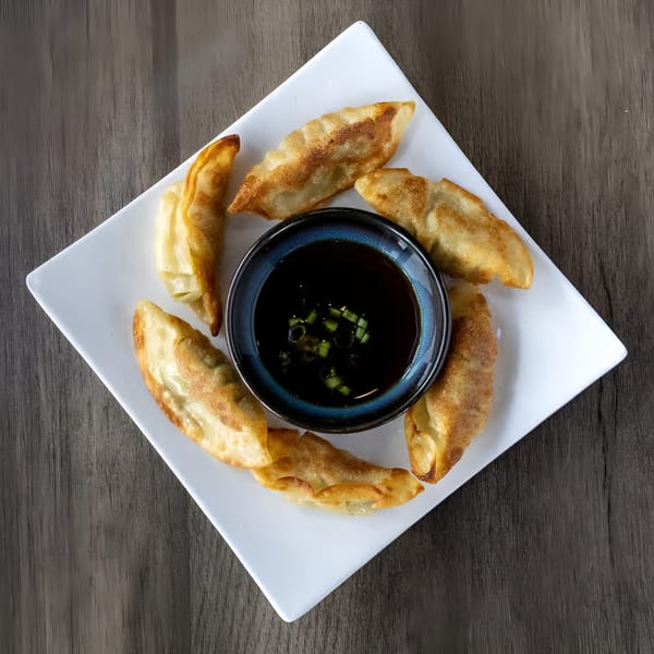 Zake's pan-fried dumplings arranged around a dark dipping sauce with green onions.