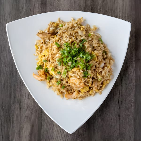 Zake's shrimp fried rice, topped with fresh green onions, served on a white triangular plate.